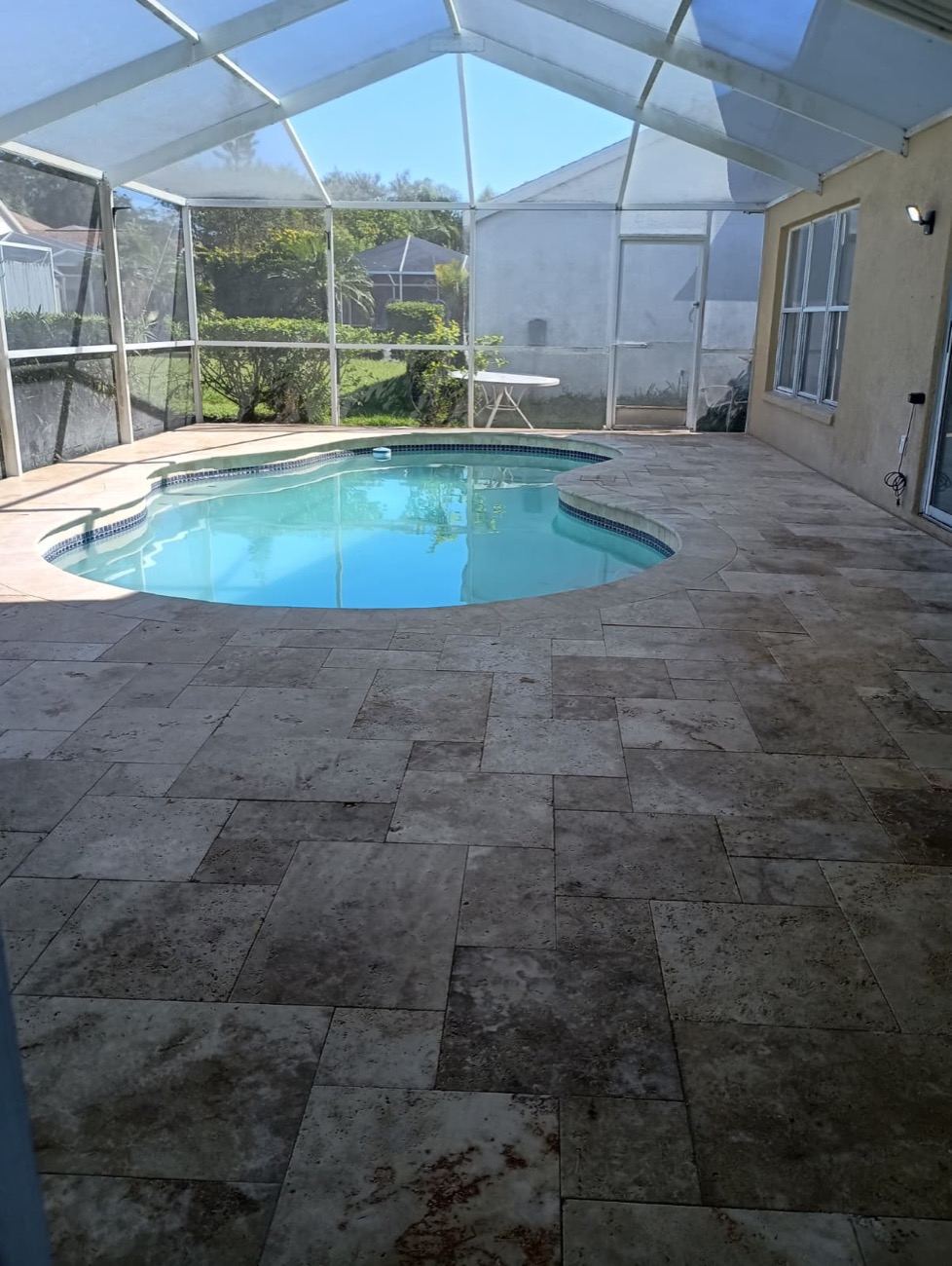 Travertine pool deck inside a screen enclosure
