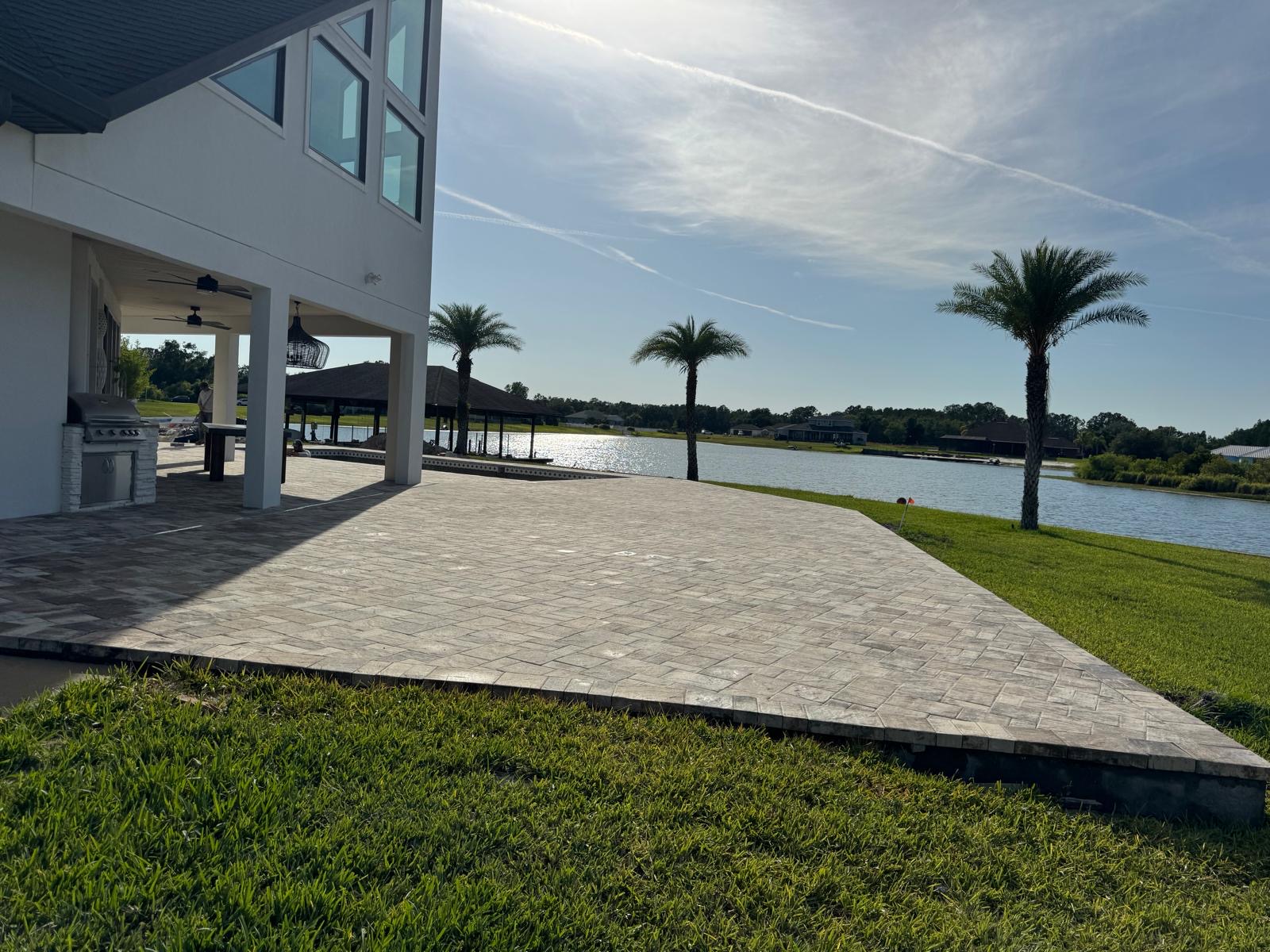 Raised paver deck overlooking the lake behind a two-story home