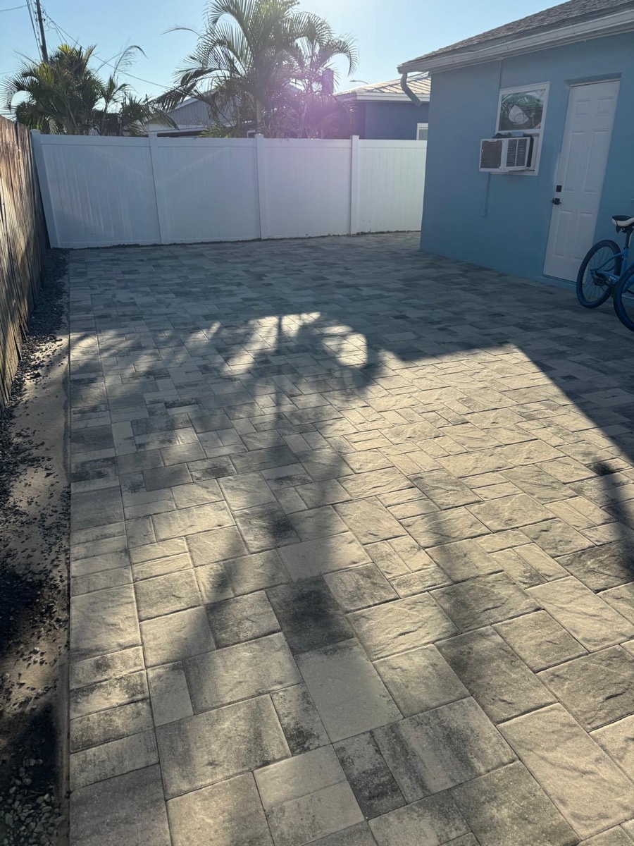 Patio in charcoal pavers next to a white fence