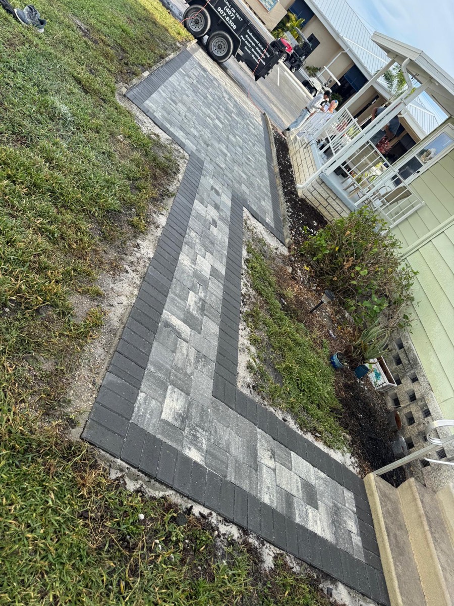 Gray paver walkway with a dark border along a side yard
